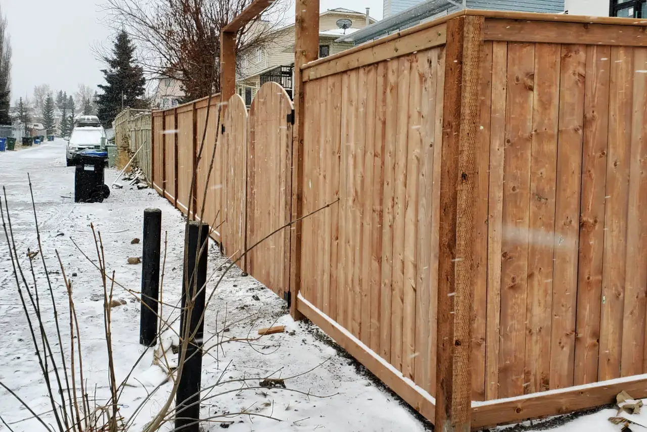 Stylish custom-built wood fence providing privacy for a home.
