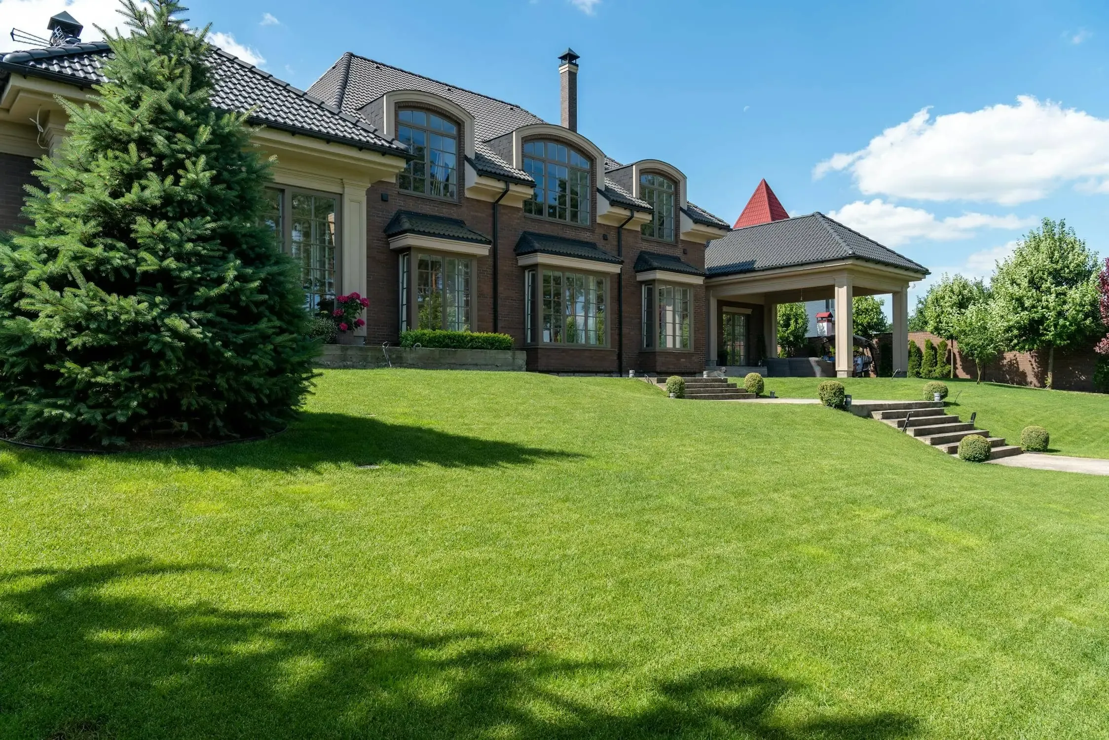 Panoramic view of a beautifully landscaped Calgary property by Bizzi Boyz Landscaping, showcasing a pristine lawn and elegant home under a clear sky.